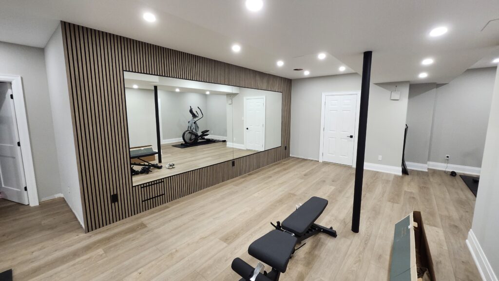 Finished basement renovation with home gym mirror feature wall flooring doors and trim in Ancaster