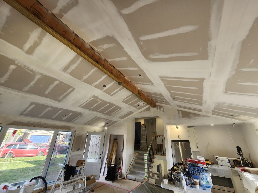 Drywall installed and taped across a new Burlington cathedral ceiling with exposed beam